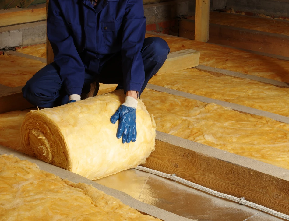 Ouvrier de construction installant des feuilles d'isolation en polystyrène sur le mur de façade de la maison pour la protection thermique