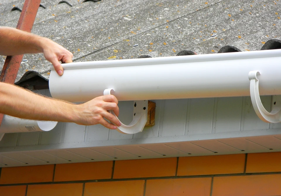 Extérieur sous forte pluie, gouttière métallique ondulée installée sur structure bois
