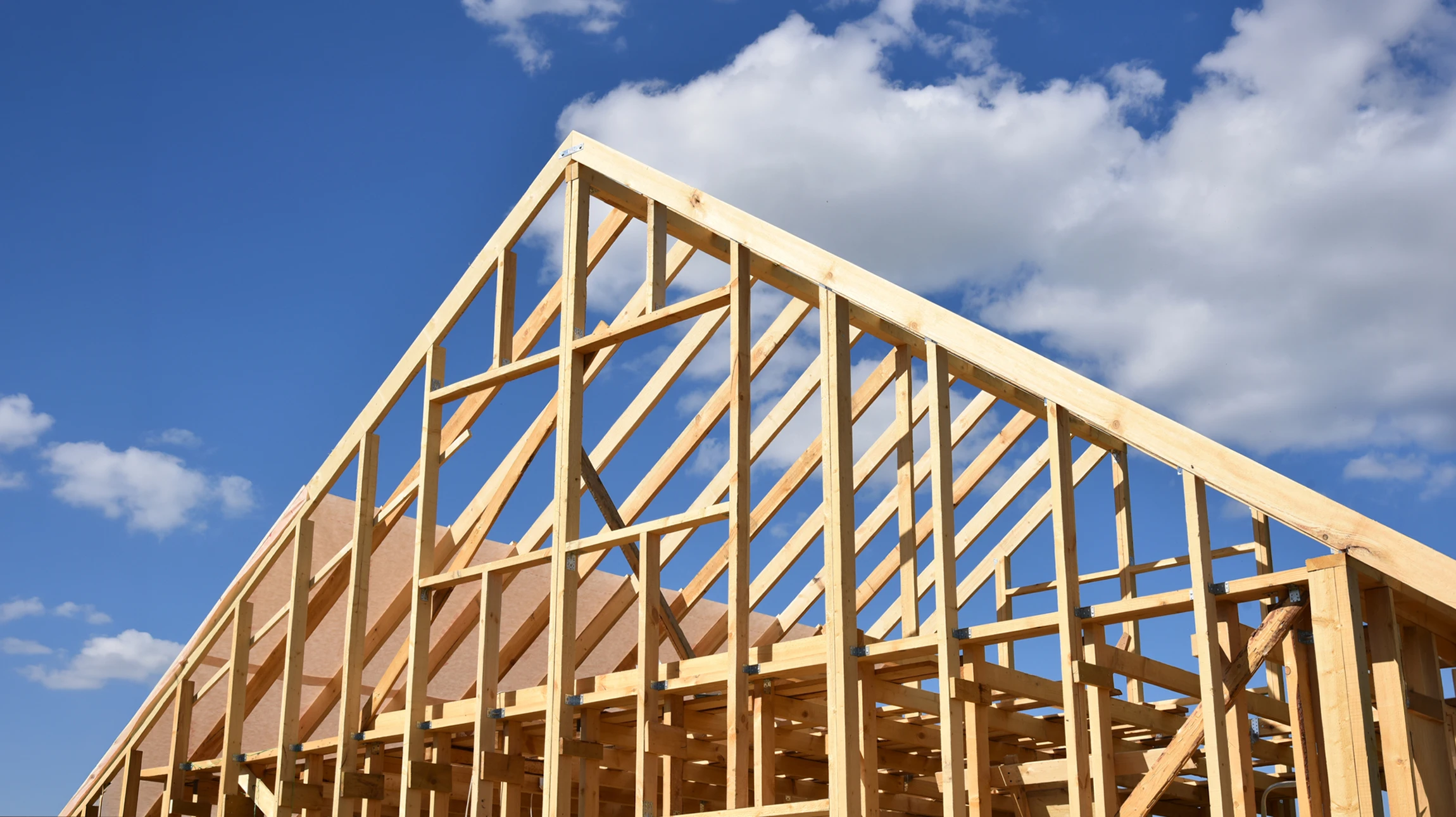 Chantier de construction extérieur avec ouvrier installant une charpente en bois