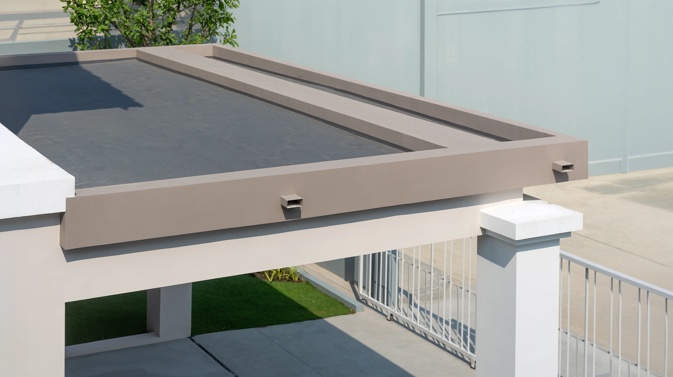 Vue aérienne d'une toiture-terrasse contemporaine avec membrane d'étanchéité blanche et parapets beiges