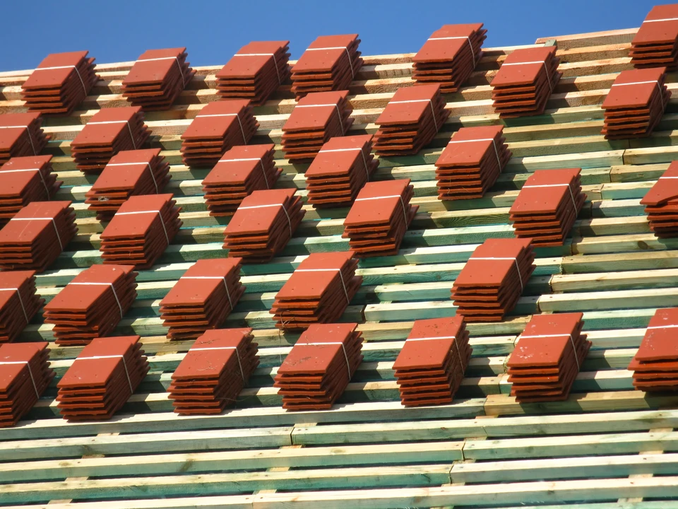 Chantier de toiture en cours avec pose de tuiles canal rouges sur charpente bois
