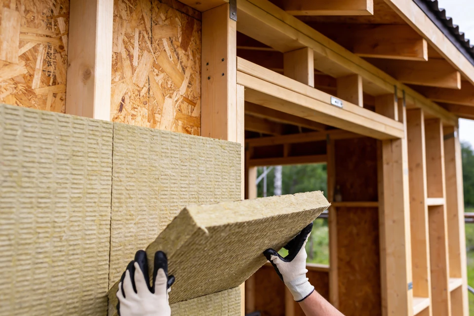 Les ouvriers installent des toits en métal sur le toit en bois d'une maison