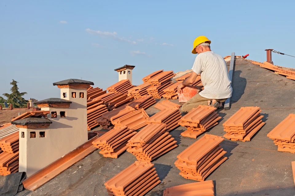 Artisan travaillant sur une toiture en rénovation, utilisant des outils de couverture